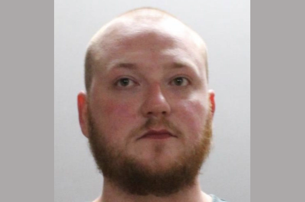Photo of an adult male with no visible hair except for a thick beard, shown from the shoulders up in a standard mugshot format.