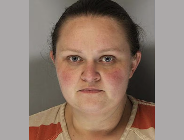 Portrait of a woman in a correctional facility shirt, looking forward with a serious expression, shown from the shoulders up.