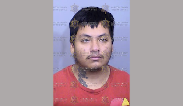 Portrait-style police photograph of a man with a serious expression, shaggy hair, facial hair, and visible neck tattoo, set against a sheriff's office-themed background.