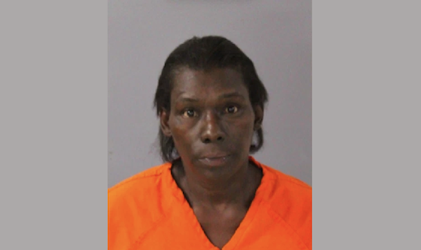 An individual wearing a bright orange jumpsuit appears in a booking photo, facing forward with a neutral demeanor.