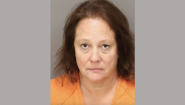 Booking photo of a woman in orange attire, with light skin and brown hair, looking directly at the camera.