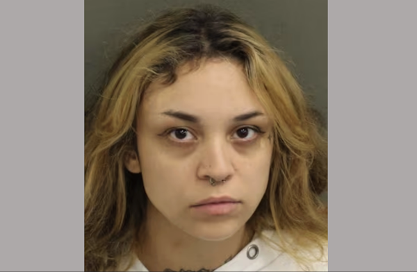 Headshot of a female subject with wavy hair, a septum piercing, and a slightly somber look, photographed for identification purposes.