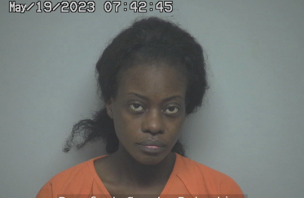 Mugshot image featuring a somber-looking woman in an orange detention outfit, with her hair partially pulled back, and a faint timestamp from May 19, 2023, displayed at the top.
