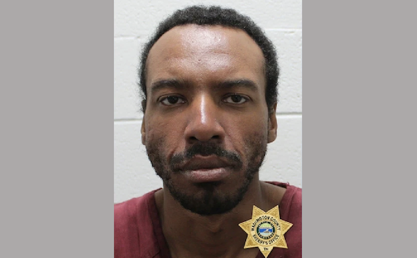 Head-and-shoulders jail intake image of a man with a beard wearing a dark red shirt.
